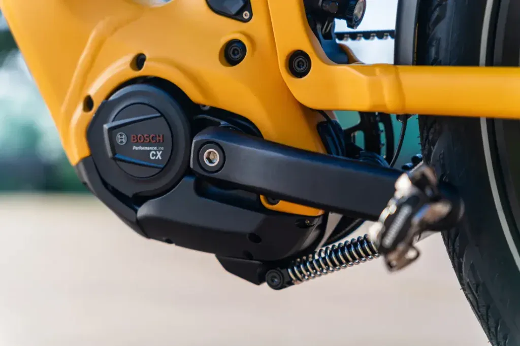 Primer plano de un motor de bicicleta eléctrica Bosch Performance Line CX amarillo y una manivela de pedal en una elegante bicicleta Velo de Ville.
