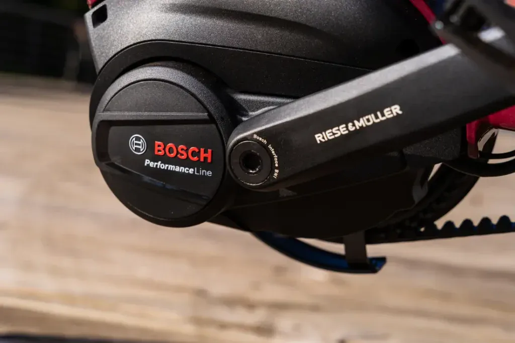 Primer plano de un motor Bosch Performance Line en una bicicleta eléctrica Riese & Müller, montado sobre una superficie de madera, mostrando su encanto de estilo urbano holandés.