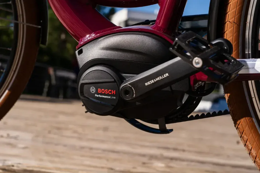 Primer plano de un motor Bosch Performance Line en una elegante bicicleta eléctrica Riese & Müller, con un fondo soleado que resalta su estilo holandés.